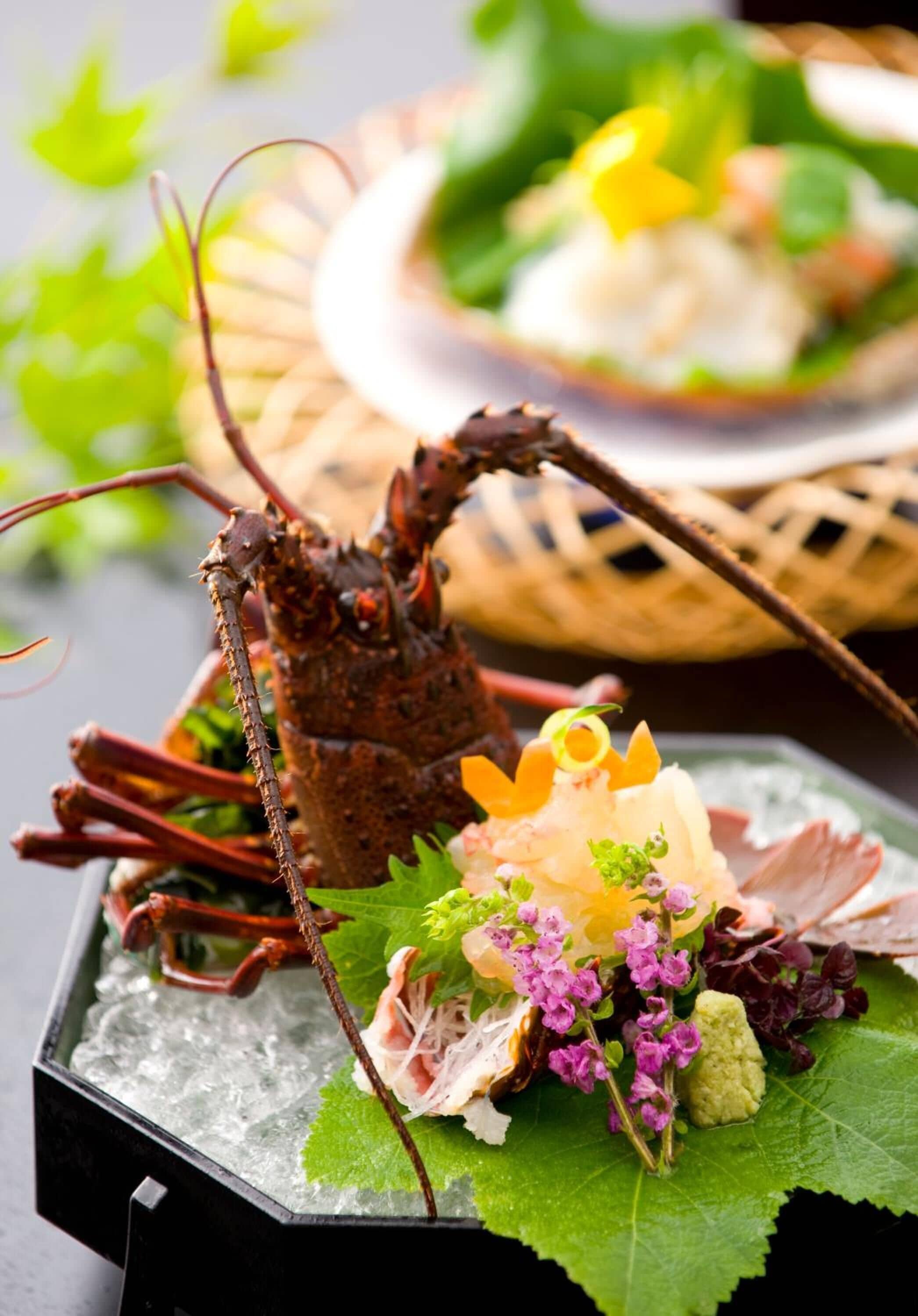 A lobster on a bed of ice with decorative flowers and greens.
