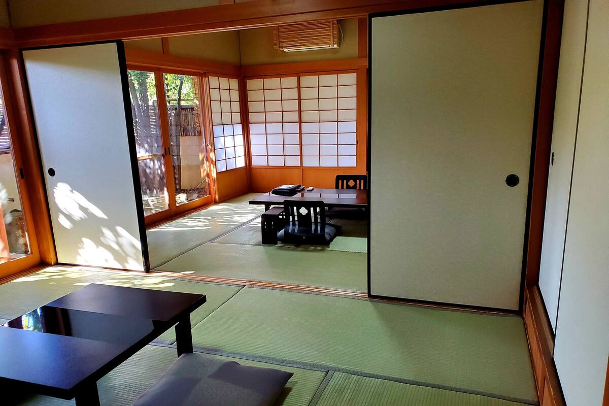 A traditional Japanese room with tatami flooring, sliding doors, and a low table with a cushion.
