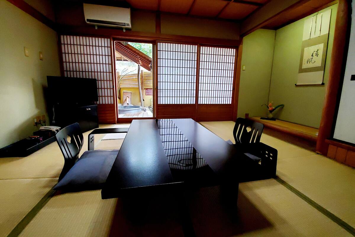 A traditional Japanese room with tatami flooring, a low table, and sliding doors.