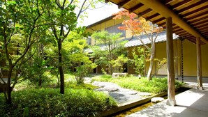 A traditional Japanese garden with a stone pathway, lush greenery, and a wooden pergola. - Yufuin Santokan (Yufu)