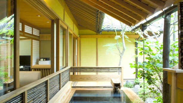A traditional Japanese onsen with wooden flooring and a wooden bench. - Yufuin Santokan (Yufu)