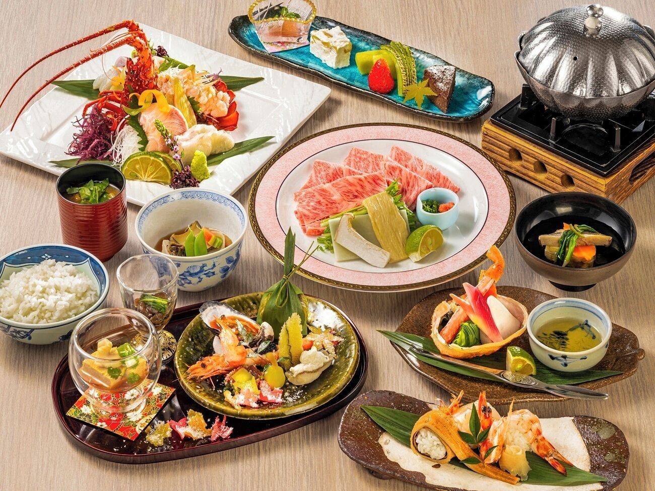 A variety of Japanese dishes including sashimi, rice, and seafood, arranged on a wooden table.