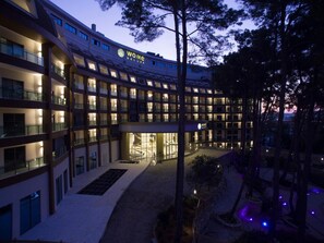 A multi-story hotel with a central courtyard, illuminated windows, and a sign reading 'WOME DELUXE'. - Wome Deluxe Hotel (Antalya)