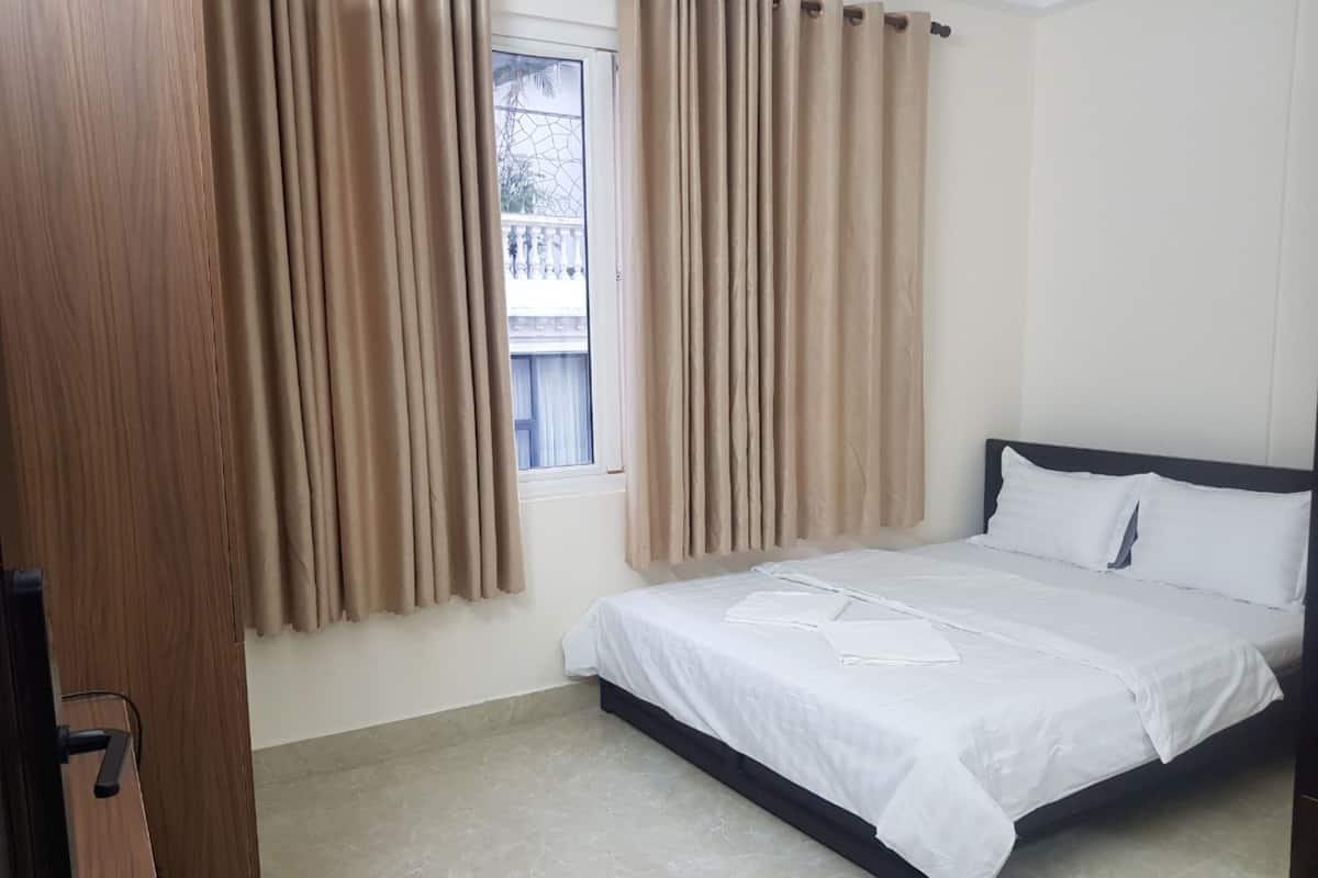 Une chambre à coucher avec un lit, des rideaux, une fenêtre et une porte.