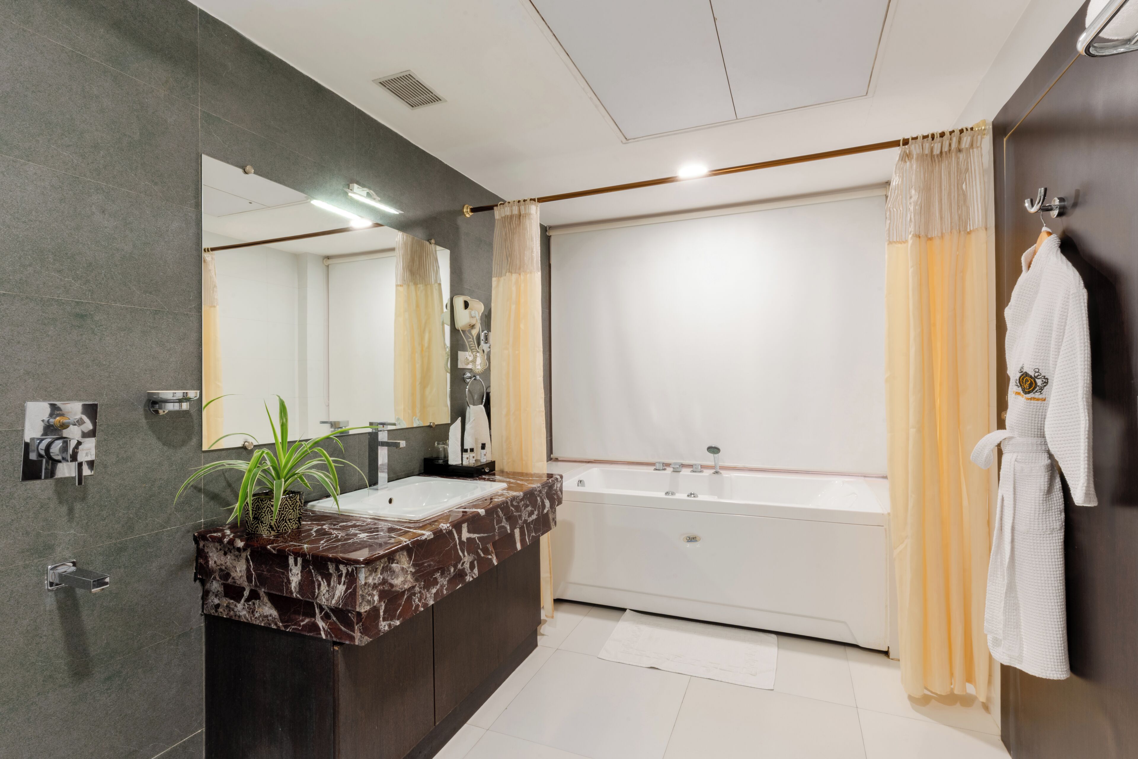 Een moderne badkamer met een marmeren wastafel, een grote spiegel, een bad en een handdoekhouder.