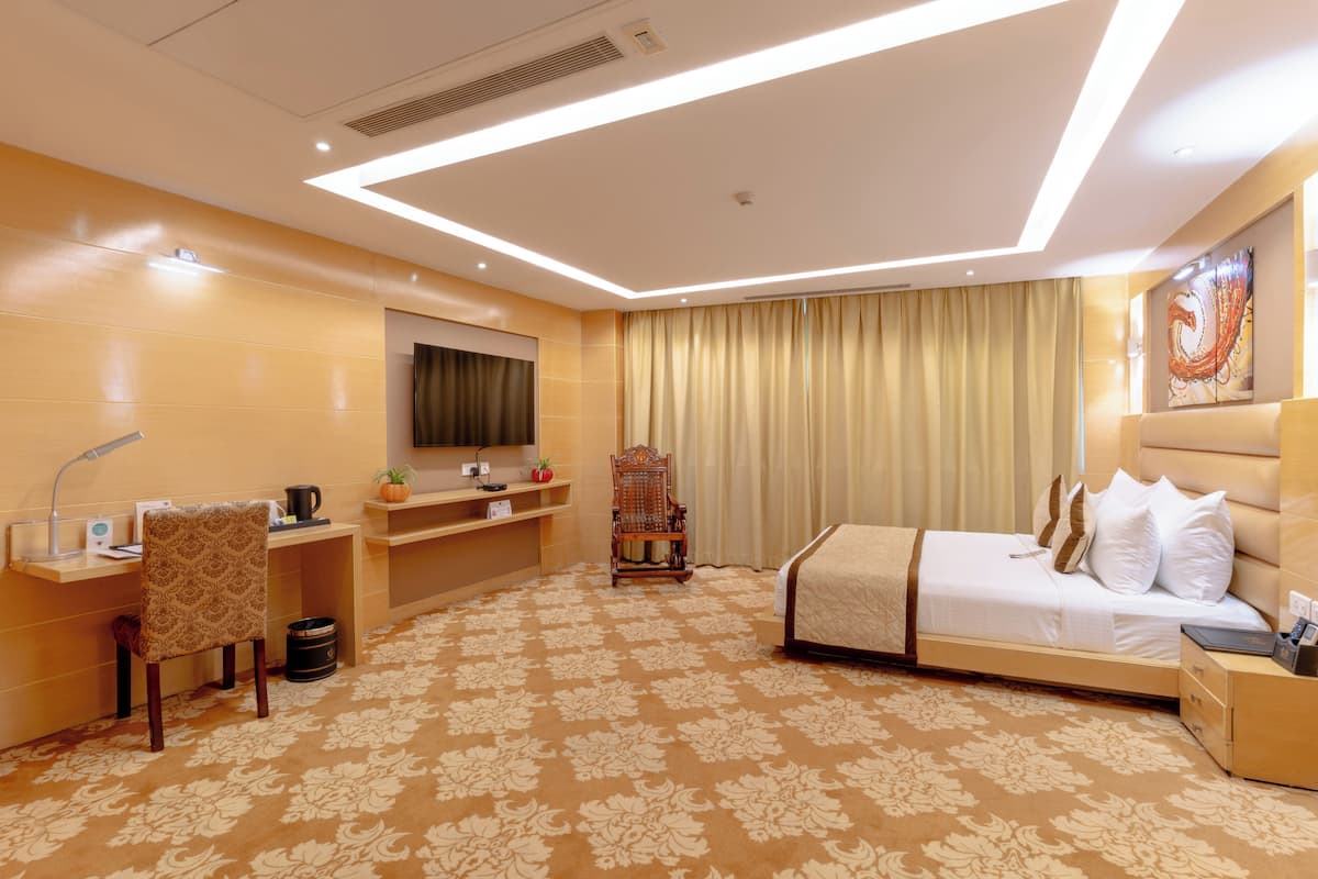 Una habitación de hotel con cama, escritorio, silla y televisor.