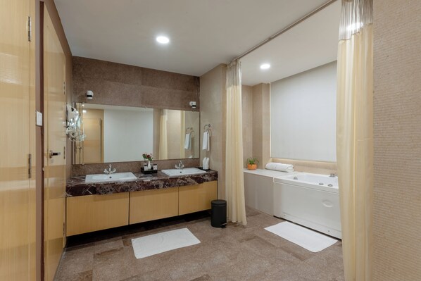 Un baño moderno con dos lavamanos, una bañera y un espejo grande.