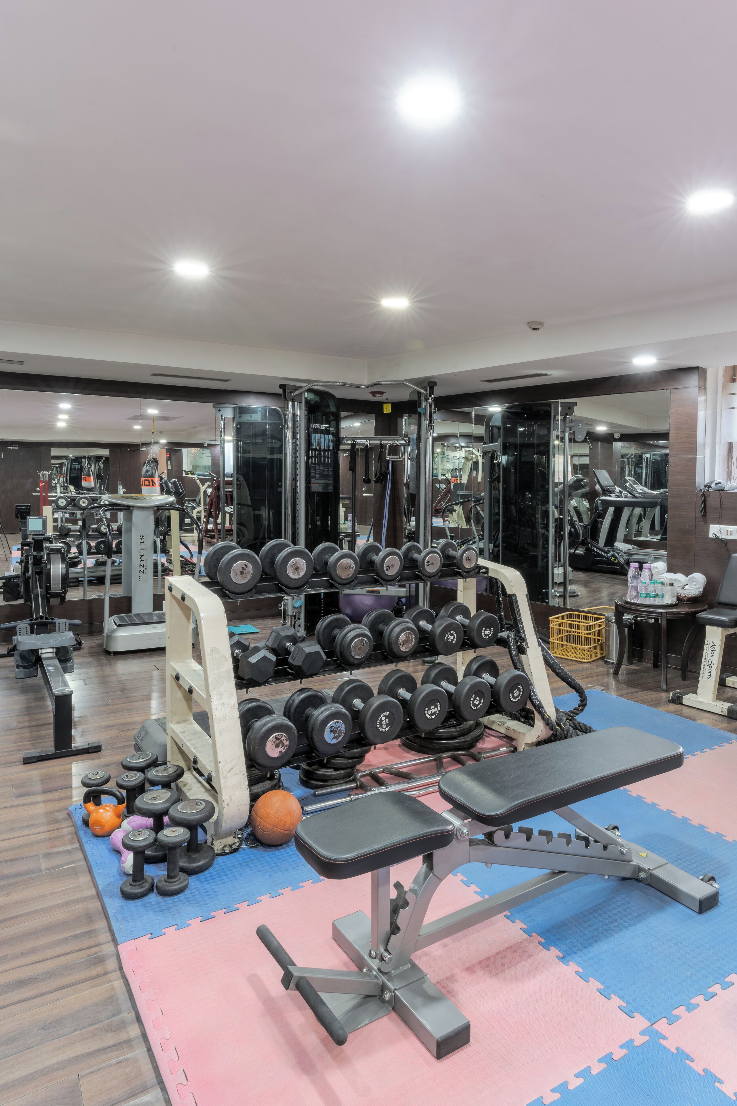 A gym with various exercise equipment, including dumbbells, a bench, and a treadmill.