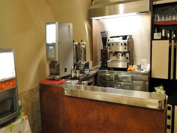 Une cuisine professionnelle équipée d’appareils en acier inoxydable, d’une machine à café et d’un distributeur de boissons.