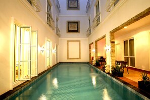 A swimming pool with a tiled floor, surrounded by walls with decorative moldings and framed artwork. - Sun Rise House (Jakarta)