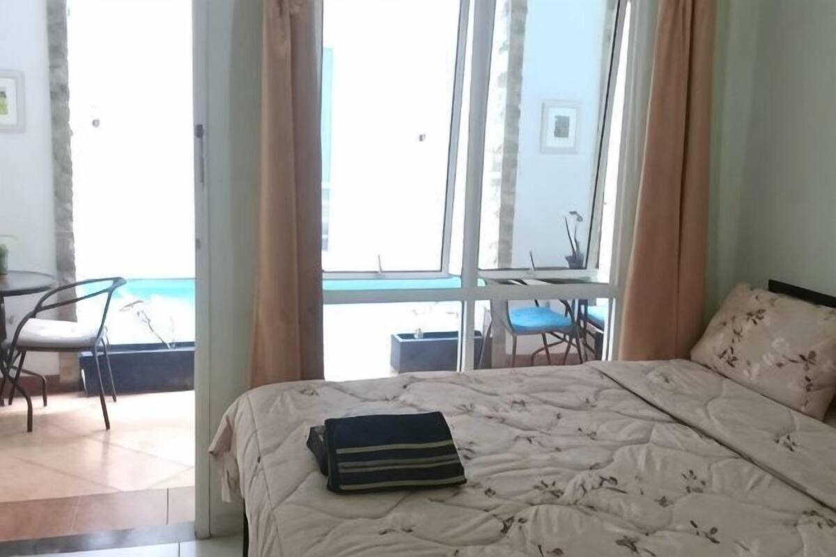 A bedroom with a bed, a window, a chair, and a table.
