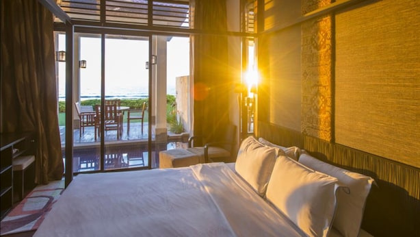 Ein Hotelzimmer mit Bett, Schreibtisch, Stuhl und Meerblick durch eine Glastür.