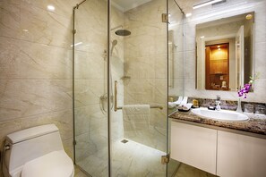 A modern bathroom with a glass-enclosed shower, a white toilet, a marble countertop, and a sink with a mirror above it.