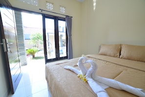 Habitación de hotel con cama, puerta corrediza de vidrio que da a un balcón y vistas al exterior.