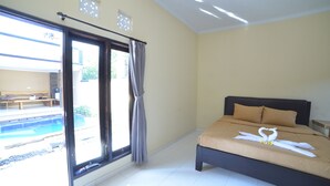 A bedroom with a bed, a sliding glass door to a pool area, and a view of the outdoors. - Ratu Guest House (Kedonganan)