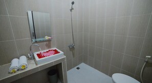 A bathroom with a white sink, a shower, and a toilet. - Ratu Guest House (Kedonganan)