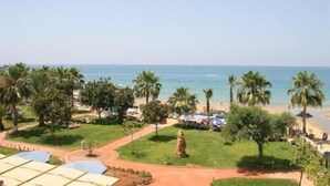 A view of a beach with palm trees, a statue, and a clear sky. - Venessa Beach Hotel (Alanya)