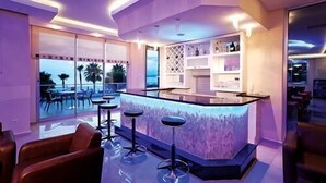 A modern bar area with a pool view, bar stools, and a wine rack. - Venessa Beach Hotel (Alanya)