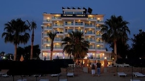 A multi-story hotel with balconies, palm trees, and beach chairs. - Venessa Beach Hotel (Alanya)