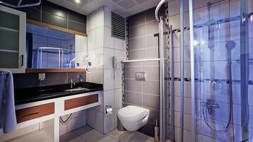 A modern bathroom with a glass shower enclosure, a white toilet, and a vanity with a mirror.