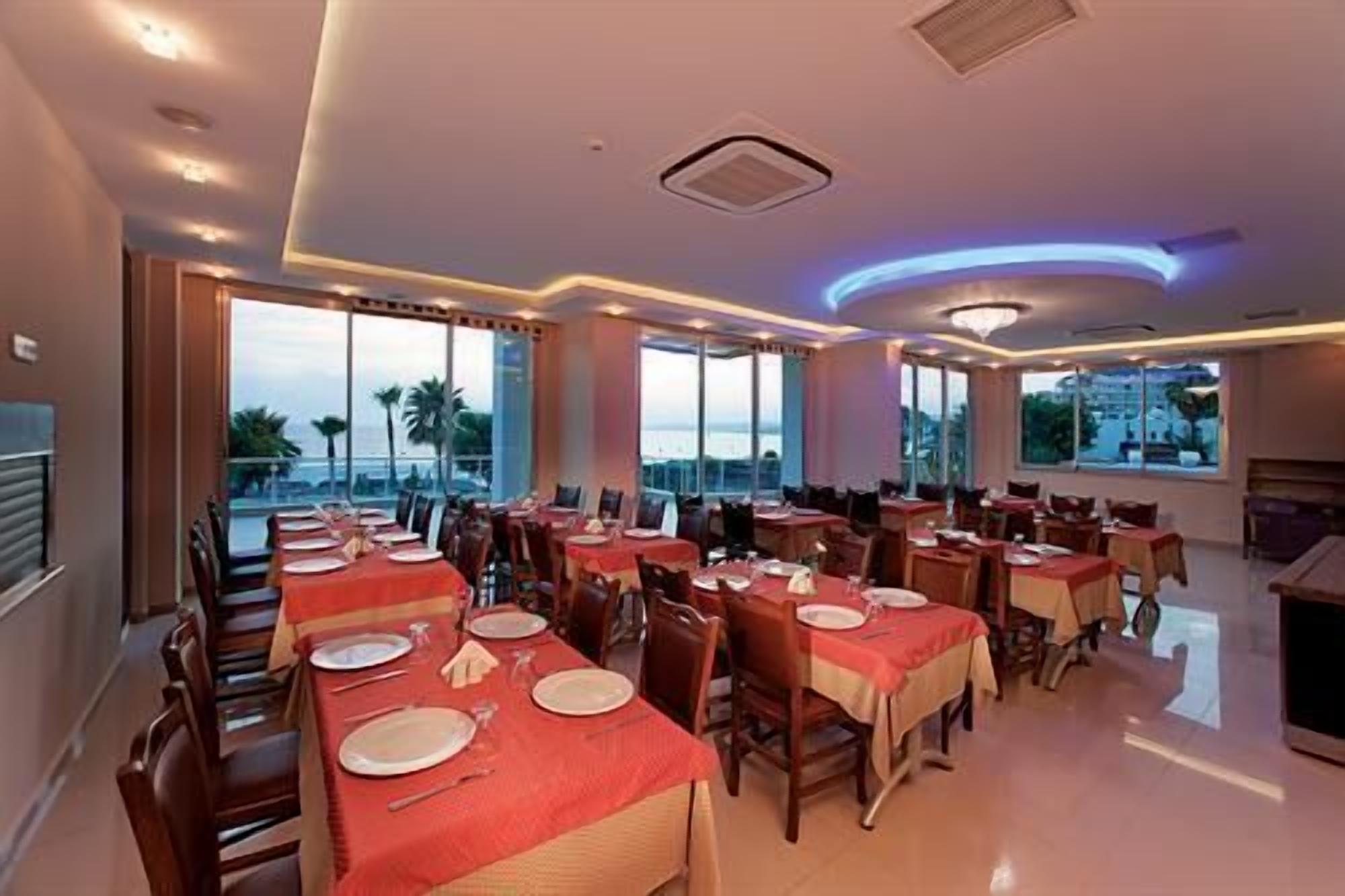 Un comedor con varias mesas, sillas y amplios ventanales que ofrecen vistas al exterior.