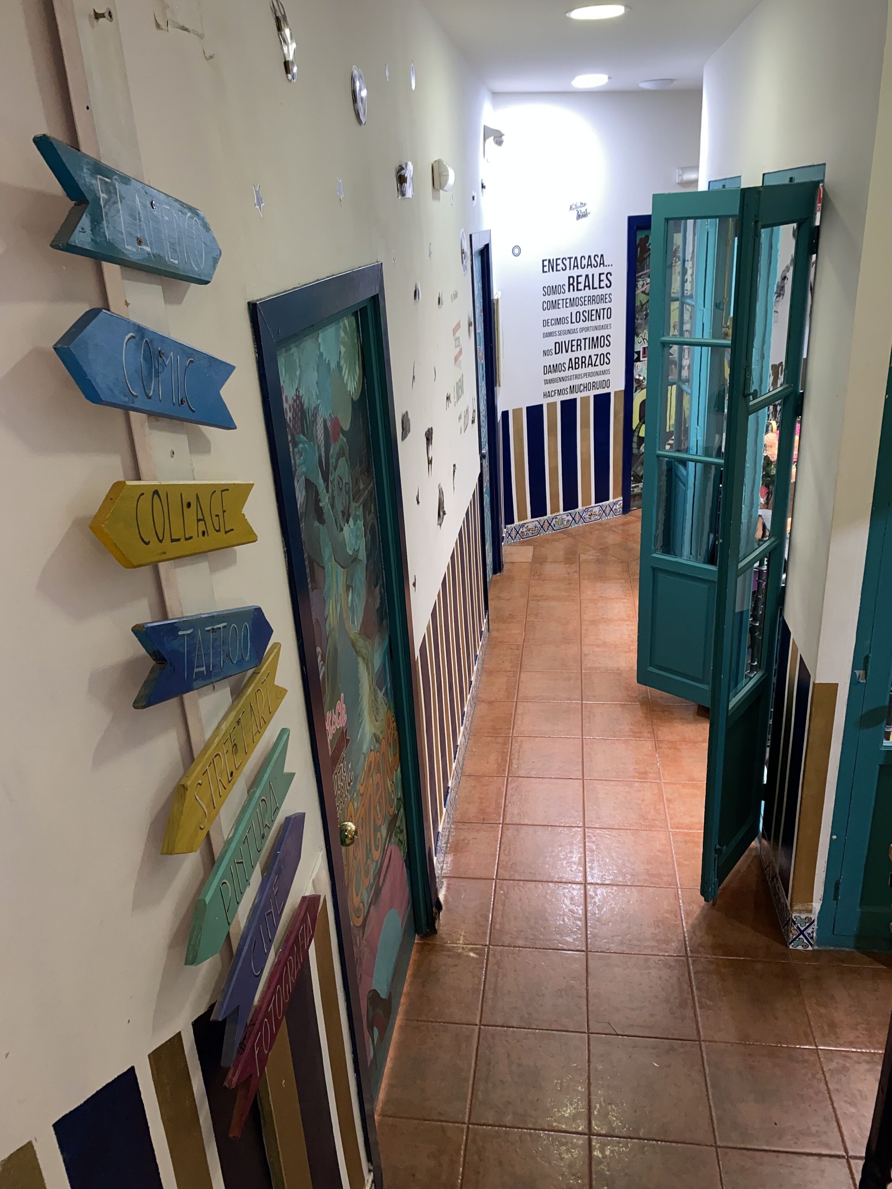 A hallway with directional signs for various services like 'COMIC', 'COLLAGE', 'TATTOO', 'STREET ART', 'PHOTOGRAPHY', and 'FASHION'.