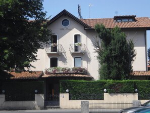 A two-story building with a balcony on the second floor, a small circular window on the first floor, and a sign above the entrance. - Hotel Ristorante Villa Monica (Prata di Pordenone)