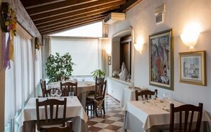 Un restaurante con varias mesas, sillas y un amplio ventanal que proporciona luz natural.