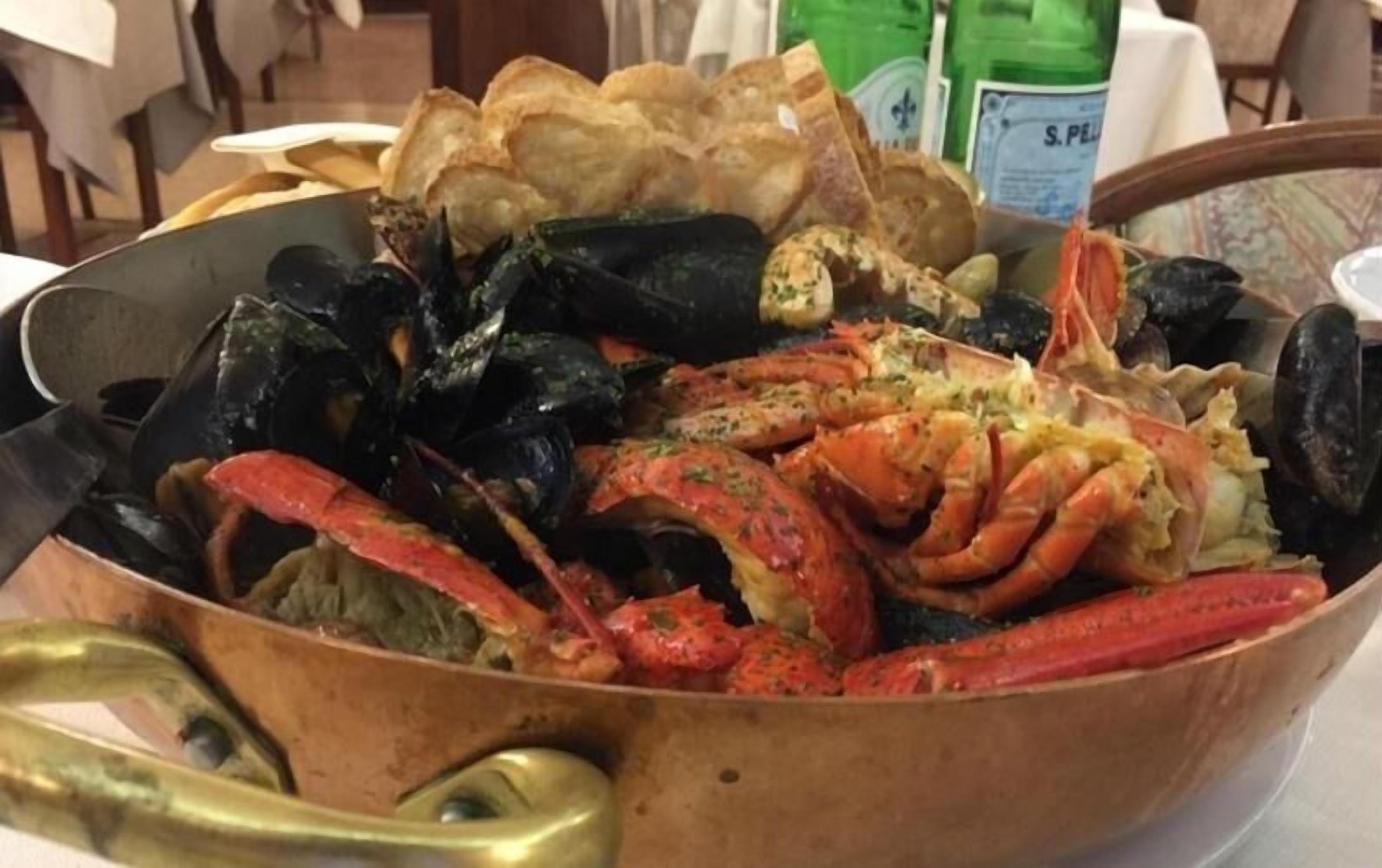 Un plato de mariscos con mejillones, camarones y langosta en una sartén de cobre.