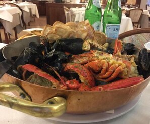 A seafood platter with mussels, crab, and bread, served on a copper platter. - Hotel Ristorante Villa Monica (Prata di Pordenone)