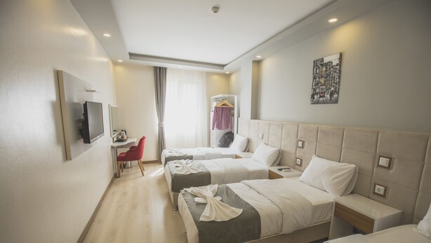 A hotel room with three beds, a TV, a desk, and a chair. - Express Inci Airport Hotel (Istanbul)