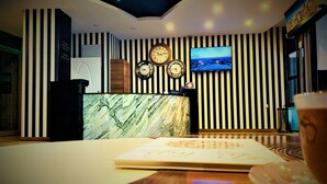 A reception area with a marble counter, clocks, a television, and a glass of a beverage. - Express Inci Airport Hotel (Istanbul)