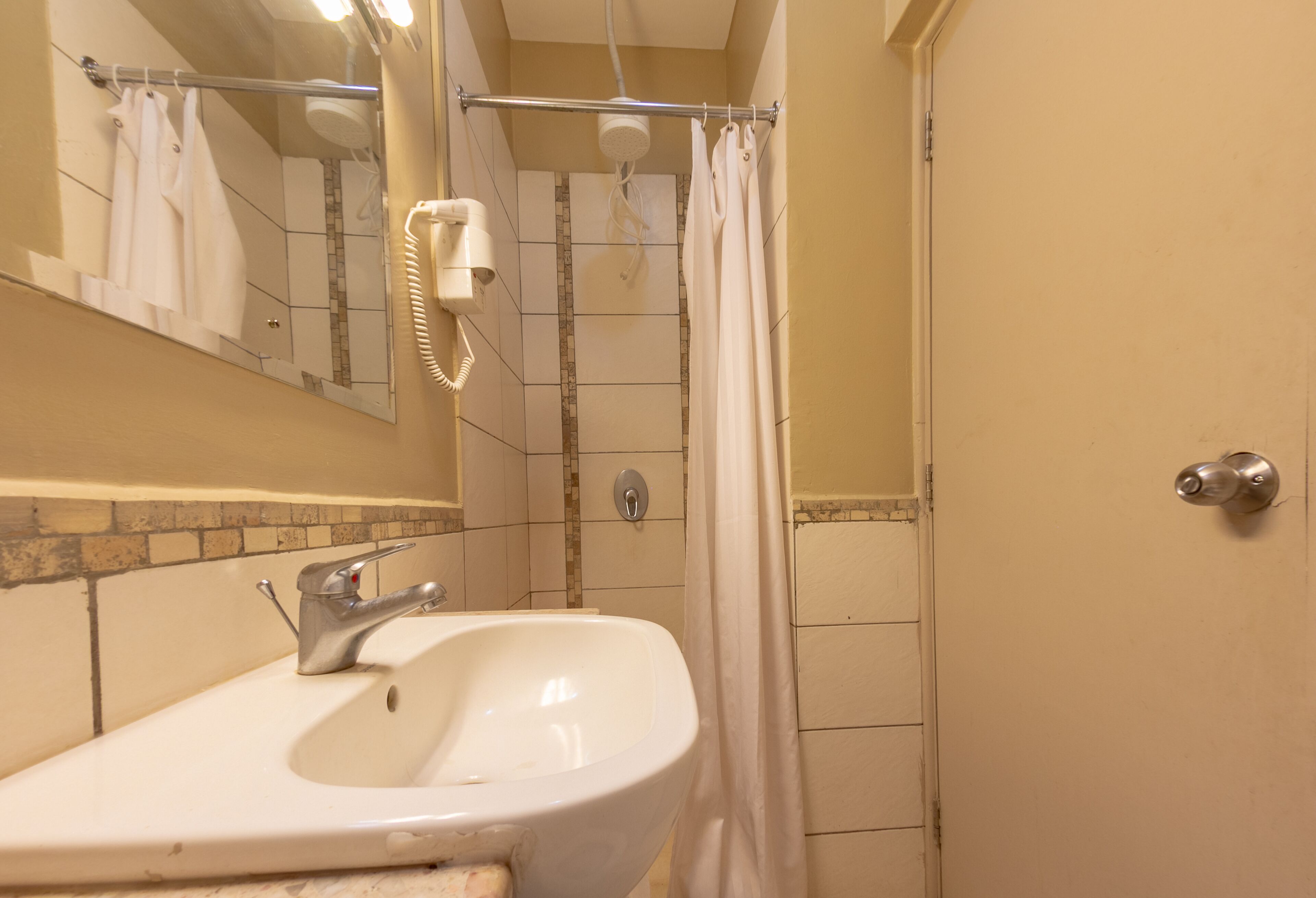 A bathroom with a sink, mirror, and shower area.