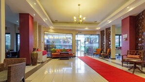 A hotel lobby with a red carpet, a sofa, wicker chairs, and a chandelier. - Hotel Rio (Nairobi)