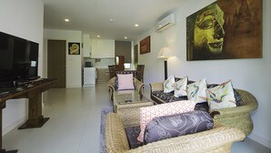 Ein Wohnzimmer mit Fernseher, Korbmöbeln und einem Buddha-Gemälde.