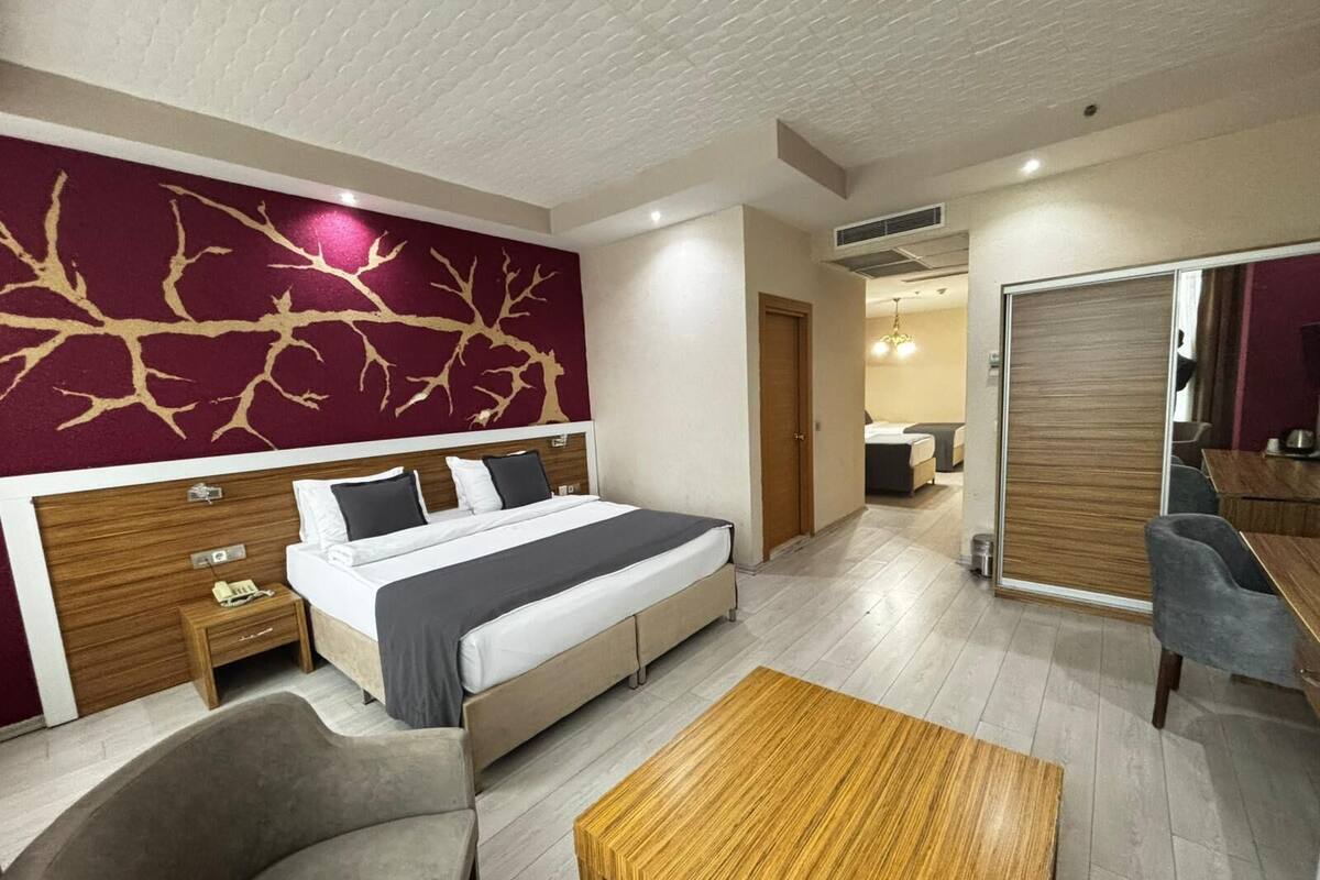 Una habitación de hotel con cama, mesita de noche, silla y una mesa de centro de madera.