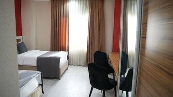 Ein Hotelzimmer mit zwei Betten, einem Schreibtisch und einem Stuhl.