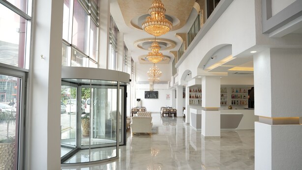 A spacious lobby with a revolving door, multiple seating areas, and a reception desk. - Mira Blue Hotel (Mezitli)