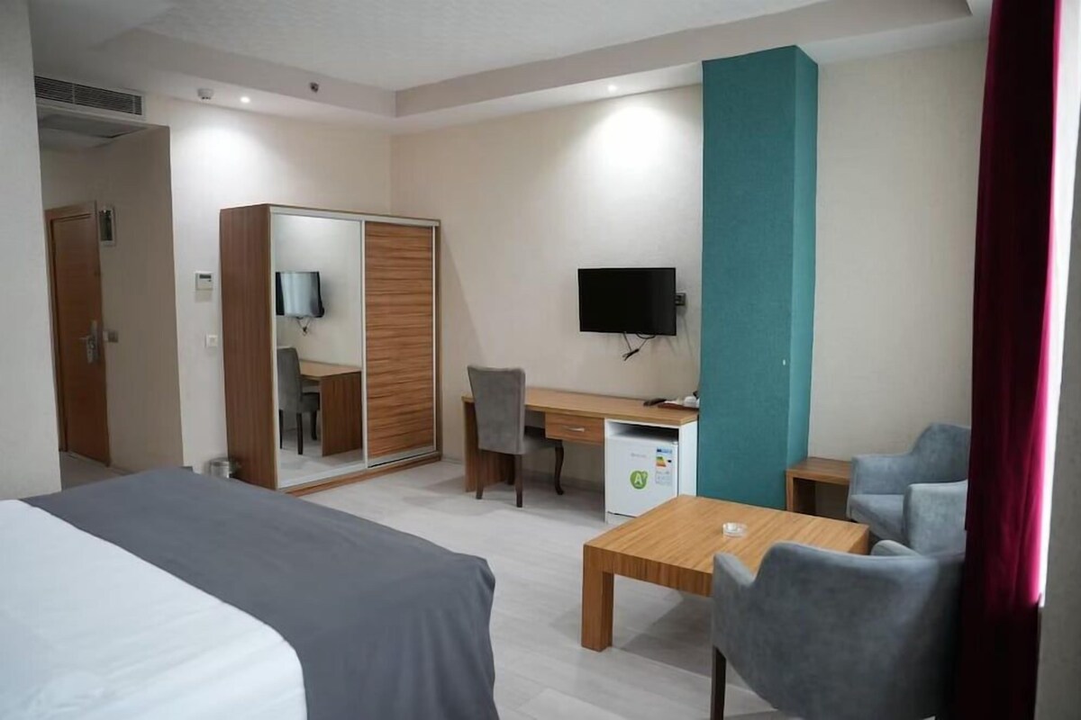 Una habitación de hotel con cama, escritorio, silla, televisor y una pequeña mesa.