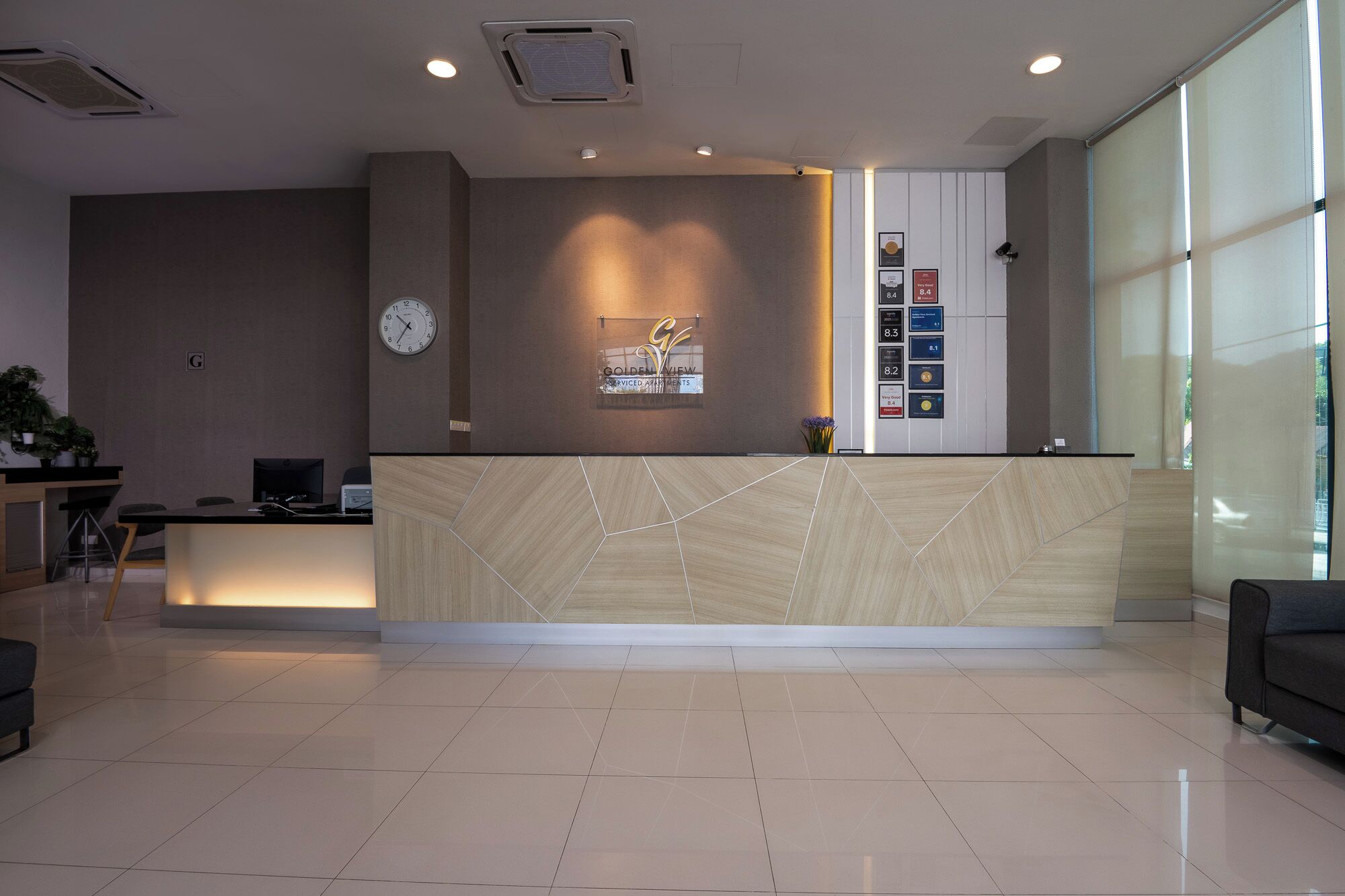 A reception area with a modern design, featuring a reception desk, a clock, and framed awards on the wall.