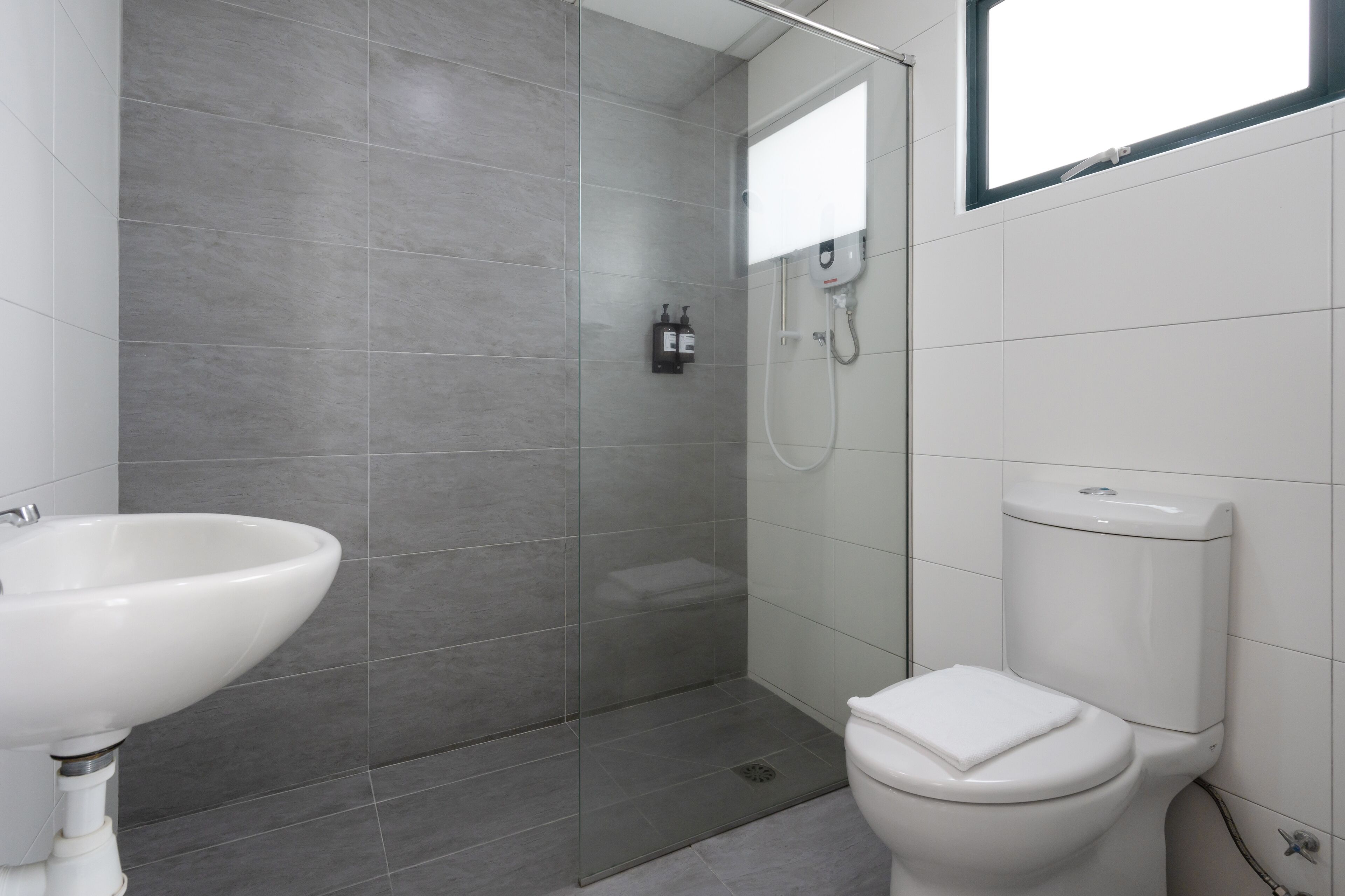 A modern bathroom with a glass-enclosed shower, a white sink, and a toilet.