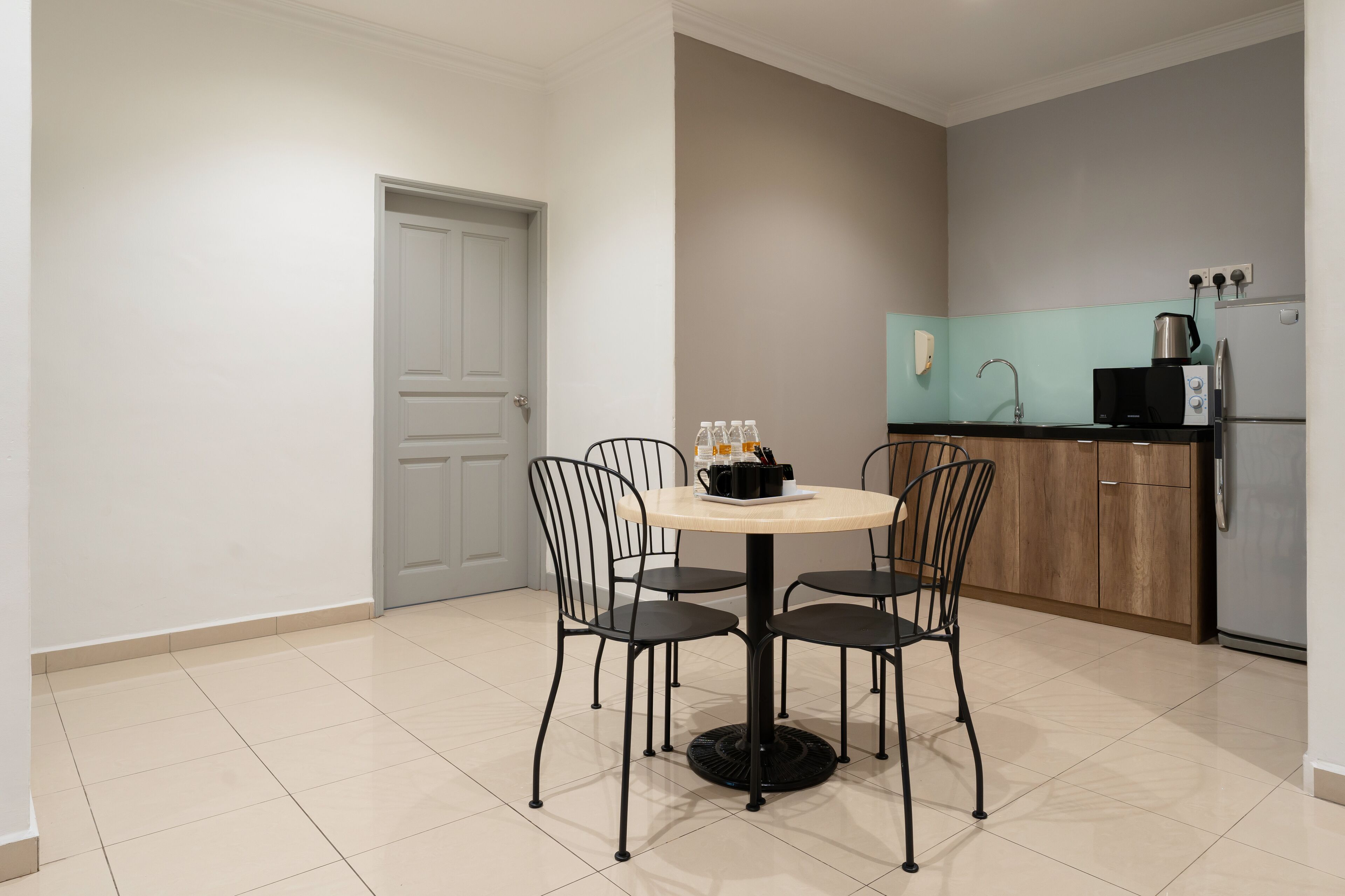 A modern kitchen with a round table and four chairs, a refrigerator, a microwave, and a coffee maker.