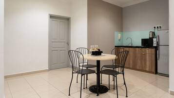A modern kitchen with a round table and four chairs, a refrigerator, a microwave, and a coffee maker.