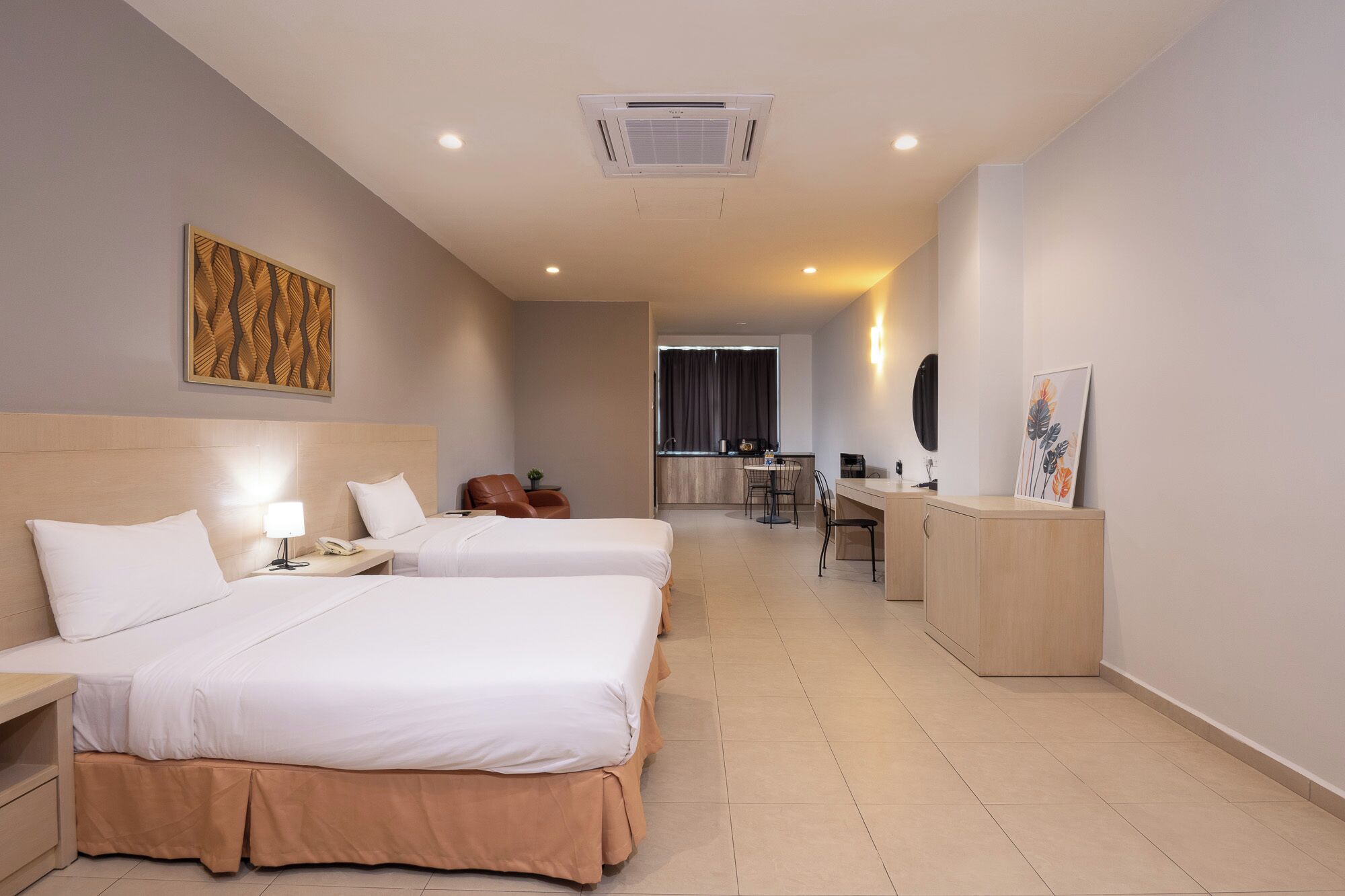 Habitación de hotel con dos camas, un escritorio, una silla, una mesita y una kitchenette.