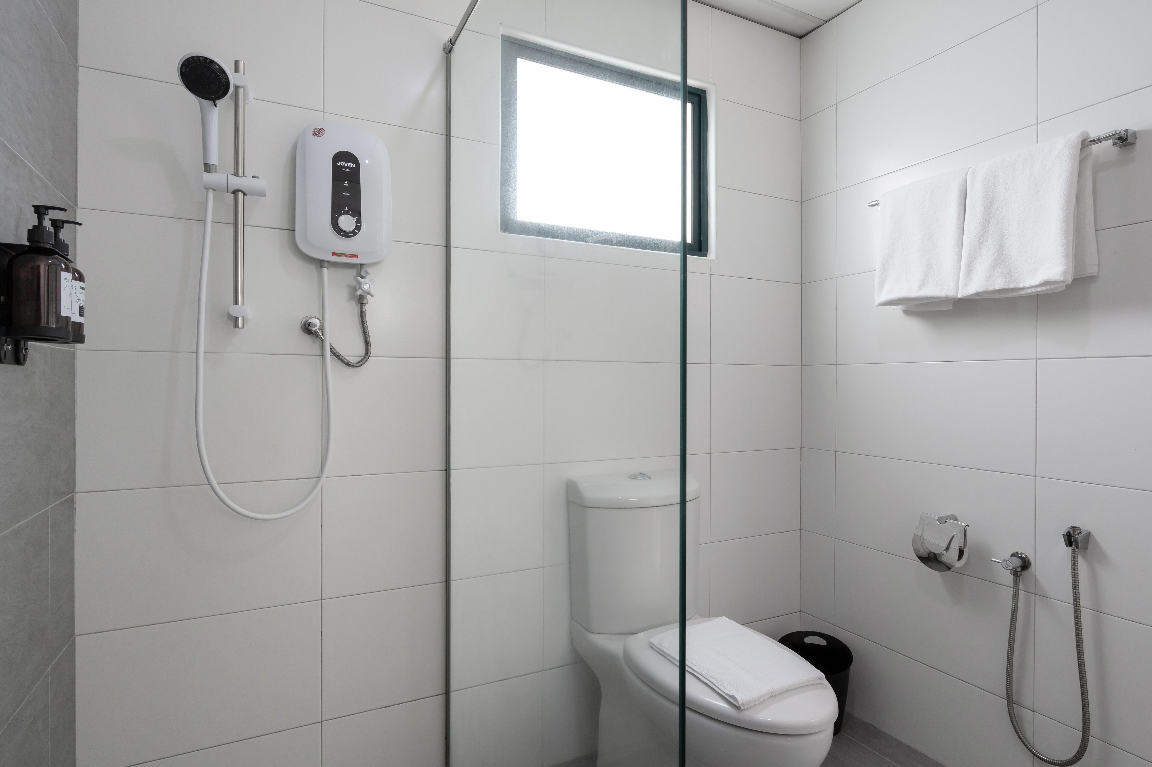 Un baño moderno con cabina de ducha de vidrio, inodoro y barra para toallas.