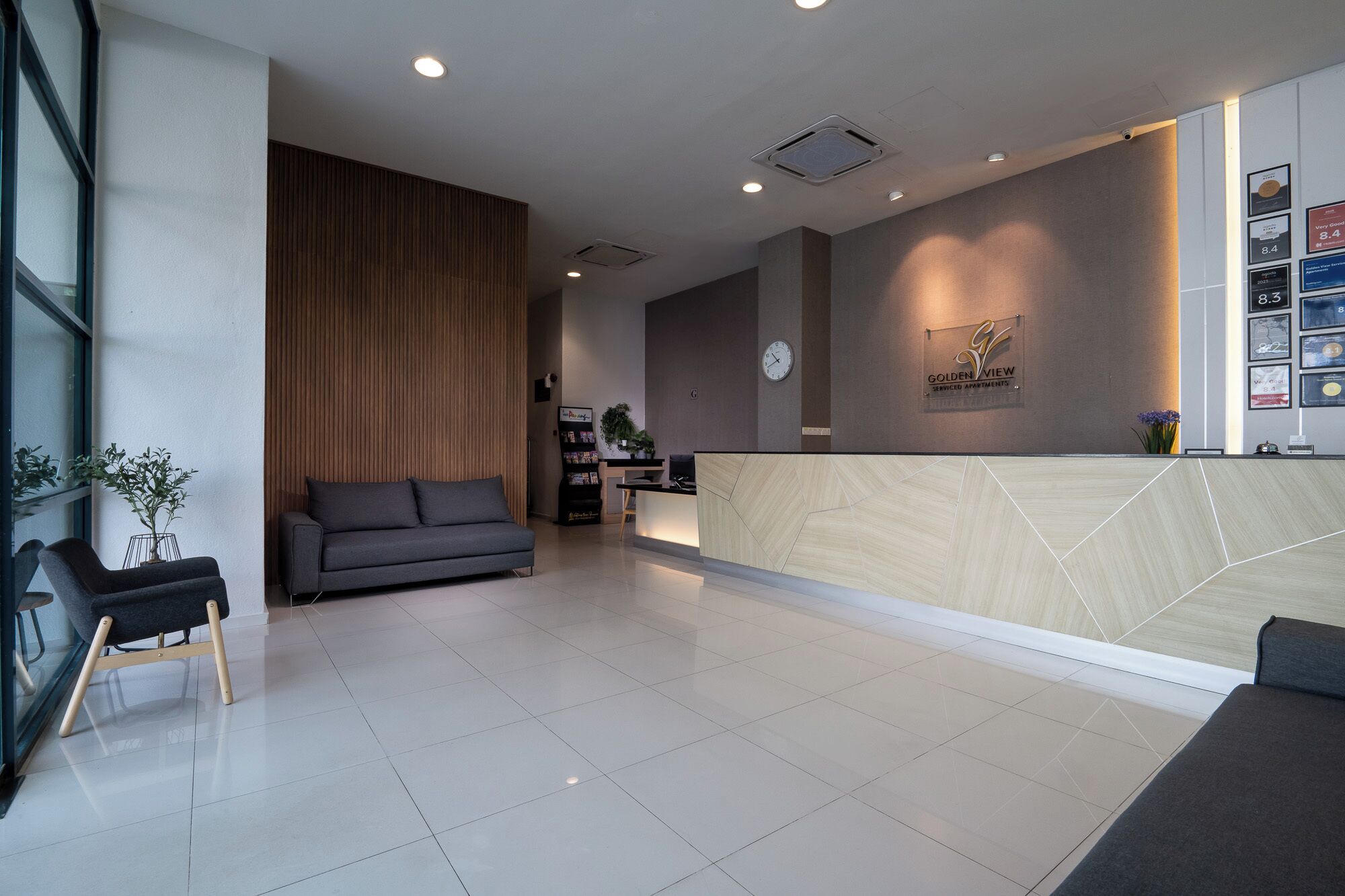 Un área de recepción moderna con un panel de madera, una mesa de recepción, un sofá y una mesa de centro.