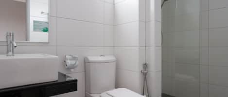 Un baño moderno con lavamanos, inodoro y ducha blancos.