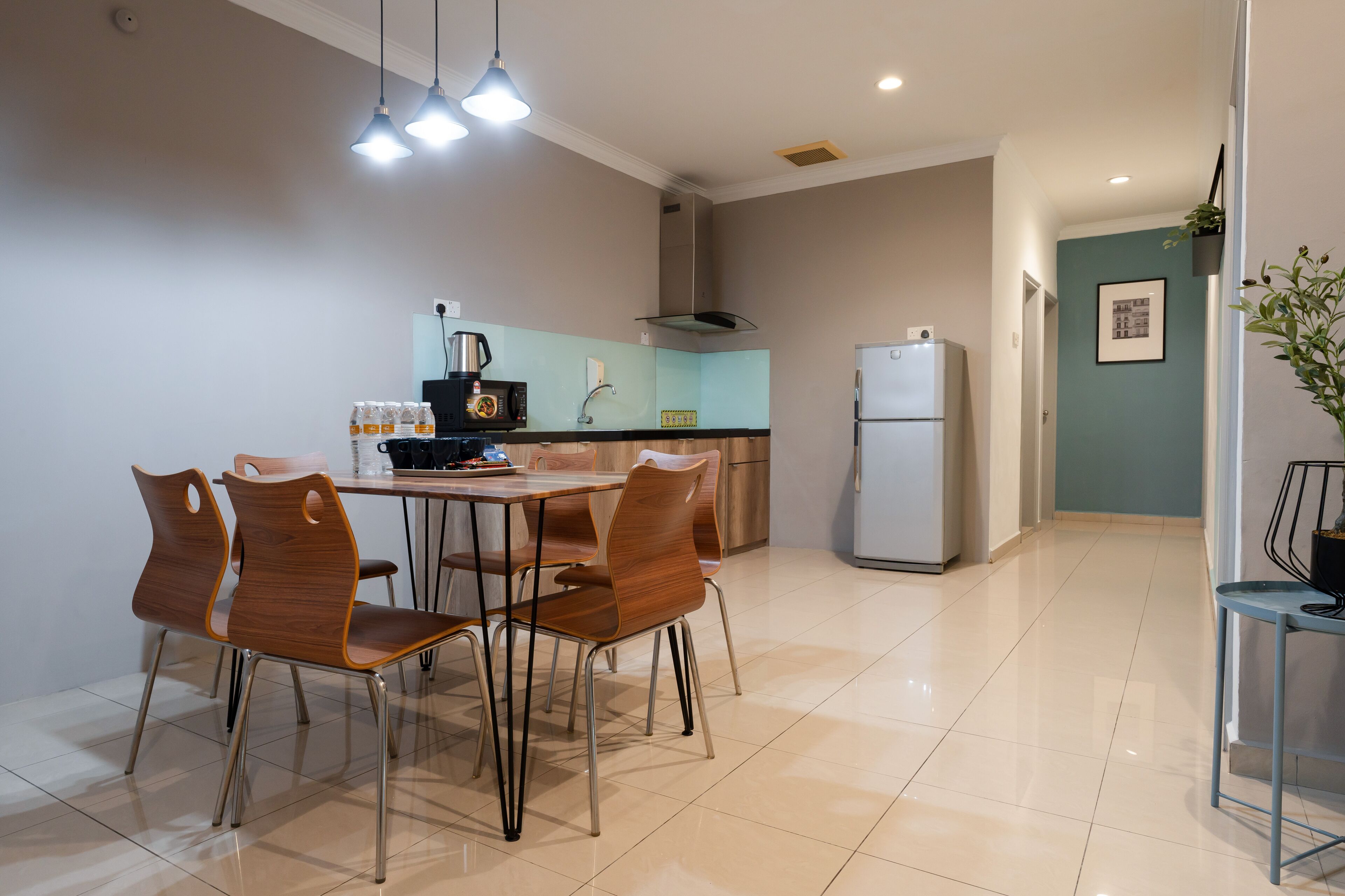 A modern kitchen with a dining area, featuring a stainless steel refrigerator, a coffee maker, and a sink.