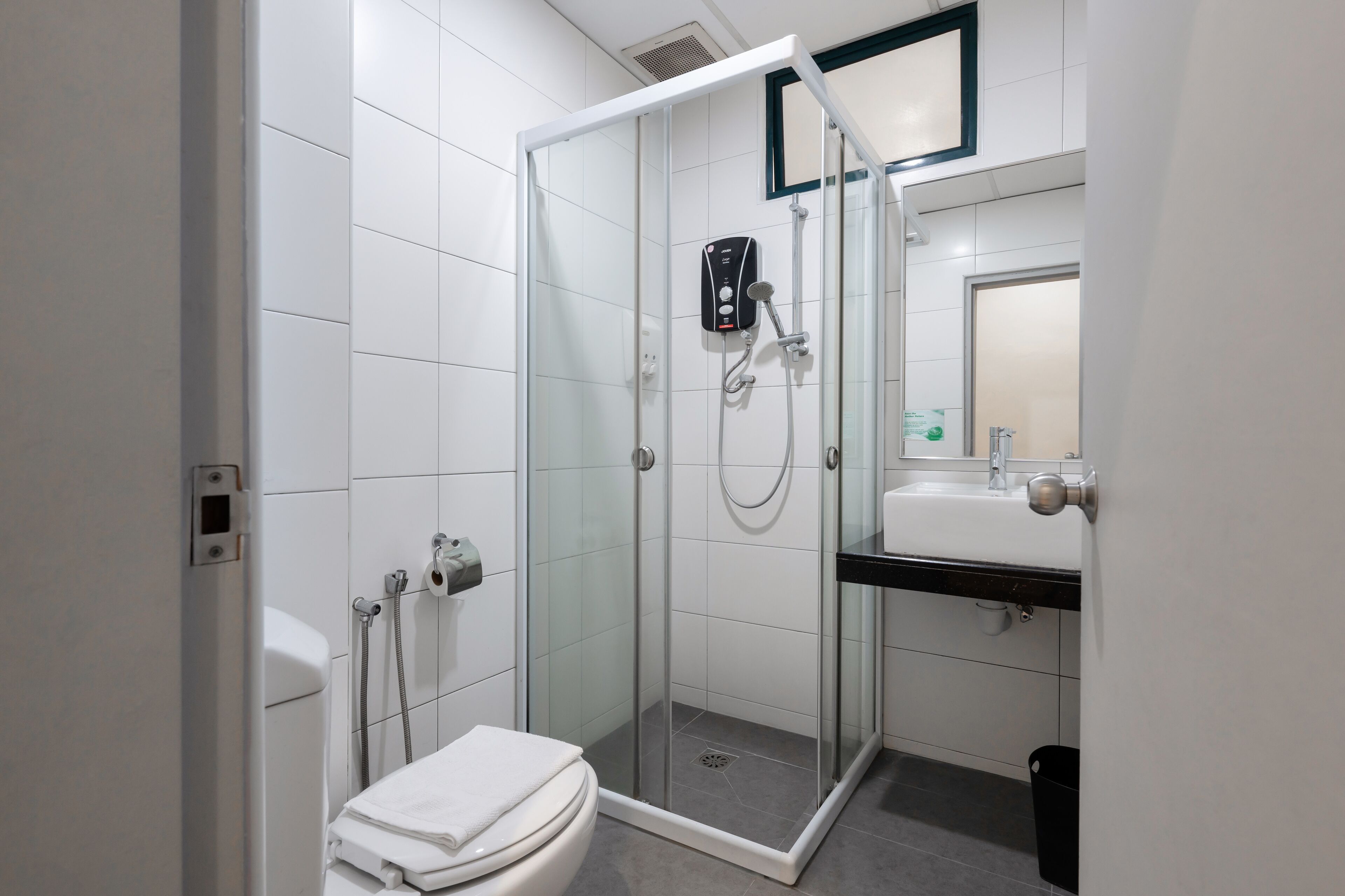 A modern bathroom with a glass-enclosed shower, a toilet, and a sink with a mirror above it.