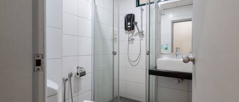 A modern bathroom with a glass-enclosed shower, a toilet, and a sink with a mirror above it.